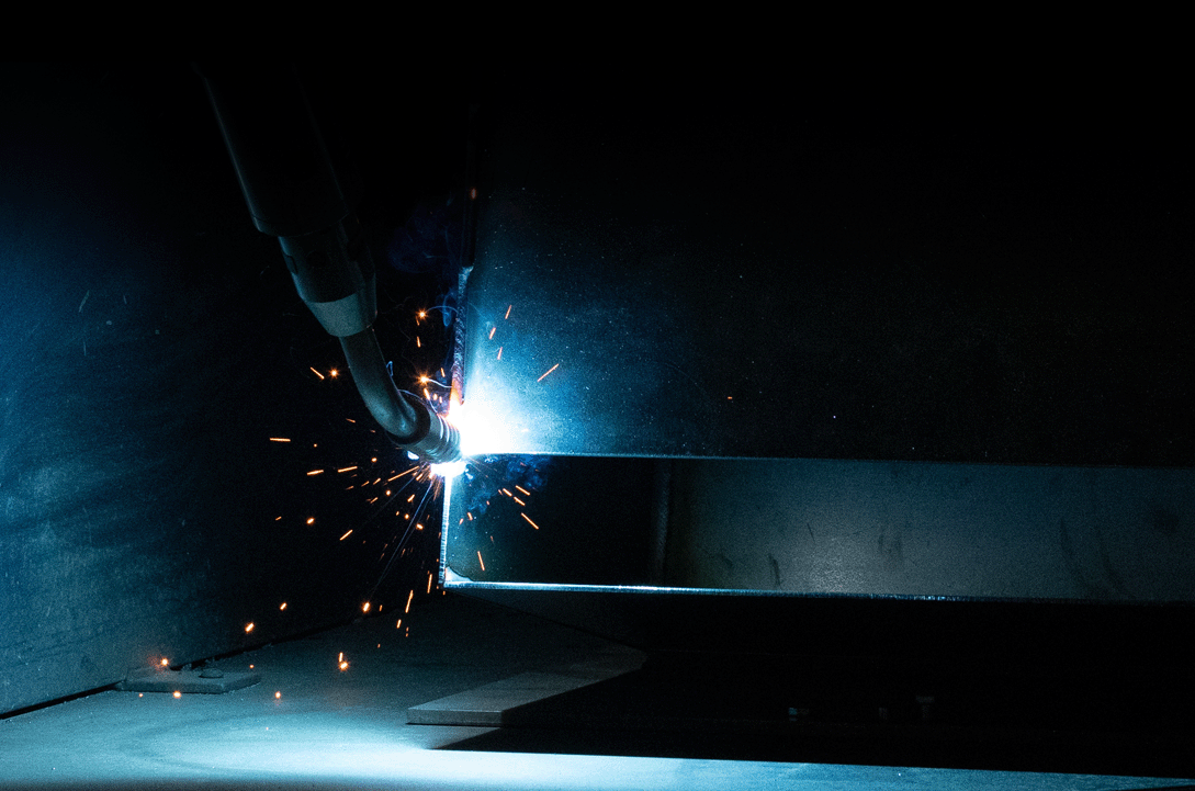 Welding arm of the robot used to weld parts in Engelbrecht Grill shop with blue sparks flying
